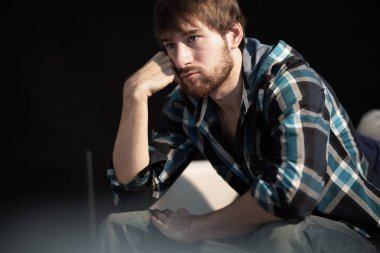 Kanepede oturup uzaya bakan üzgün genç adam