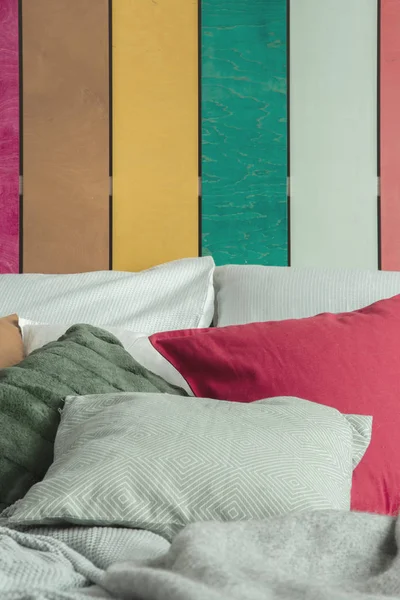 Zbliżenie zielone, czerwone i szare poduszki na przytulnym łóżku z kolorowych ścian za — Zdjęcie stockowe
