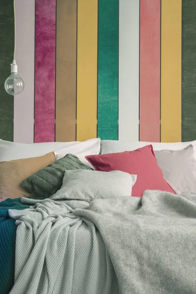 Крупним планом ліжко королівського розміру з зеленими, жовтими, червоними та сірими подушками — стокове фото