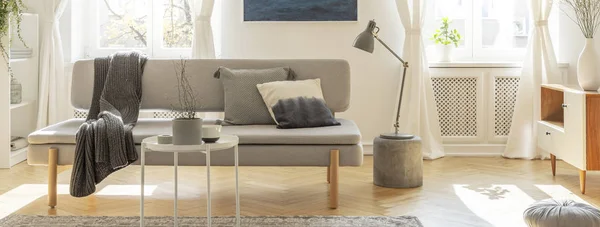 Szara lampka na małym stoliku obok wygodnej sofy z poduszkami — Zdjęcie stockowe