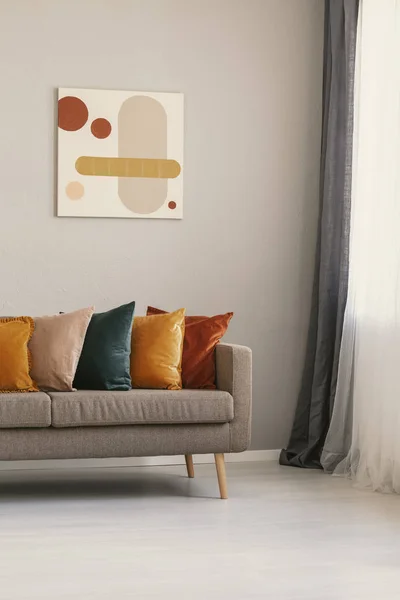 Abstrakt målning på beige vägg ovanför brun soffa med färgglada kuddar — Stockfoto