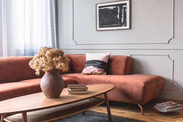 Fleurs brunes dans un vase en poterie sur une table basse élégante dans un salon chic intérieur avec affiche en noir et blanc sur le mur gris — Photo