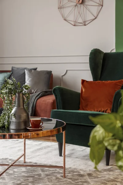 Коричневый бархатный угловой диван и изумрудно-зеленое заднее кресло в гостиной — стоковое фото