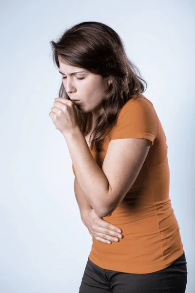 Junge hübsche brünette Frau trägt orangefarbenes T-Shirt und hustet — Stockfoto