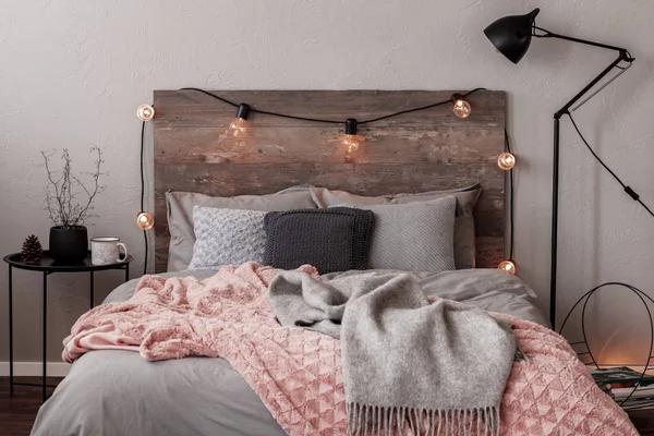 Grijs en pastel roze deken op grijs beddengoed van modieuze slaapkamer met rustiek design — Stockfoto