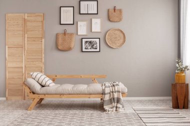 Yastık ve battaniye ile uzun settee ile trendy oturma odası iç bej duvara siyah çerçeveler ve hasır kinck pnack posterler Galerisi