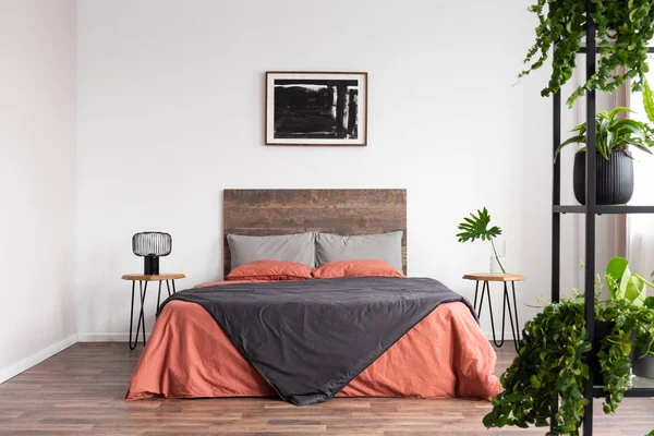 Плакат на белой стене элегантного интерьера спальни с кроватью размера "king-size" с деревянной изголовьем — стоковое фото