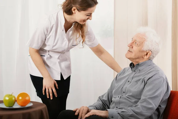 Viejo en un asilo de ancianos con cuidador servicial a su lado — Foto de Stock