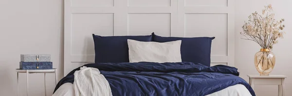 White pillow in the middle of king size bed with blue duvet, copy space on empty wall — Stock Photo, Image