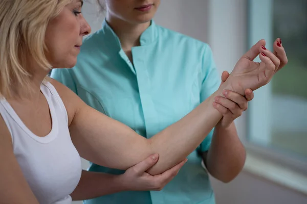 Seniorin arbeitet mit junger professioneller Physiotherapeutin zusammen — Stockfoto