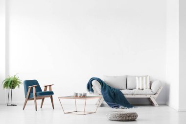 Parlak bir oturma odasının gerçek fotoğrafı. Koltuğu, koltuğu ve kahve masası var. Boş duvar, tablonu yerleştir.