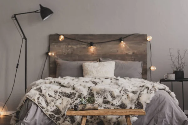 Wooden bench in the foot of the bed with grey bedding and cozy blanket — 스톡 사진