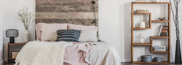 Vista panorámica de la cómoda cama con sábanas de color rosa pastel y manta blanca en el dormitorio de moda en estilo rústico —  Fotos de Stock