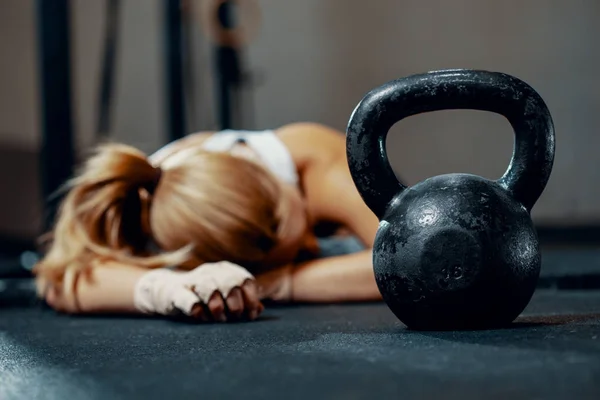 Mladá vyčerpaná dívka ležící na podlaze fitness centra po tréninku — Stock fotografie