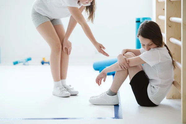 Colegiala se acerca a su triste amigo en el gimnasio —  Fotos de Stock