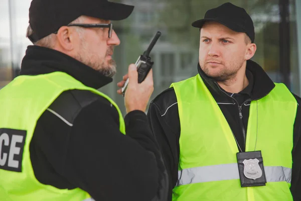 Zbliżenie policjantów mówiących przez krótkofalówkę podczas interwencji — Zdjęcie stockowe