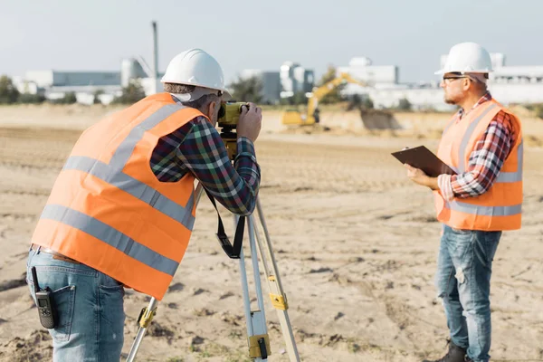 Two road construction workers using measuring device on the field — Stock Photo, Image