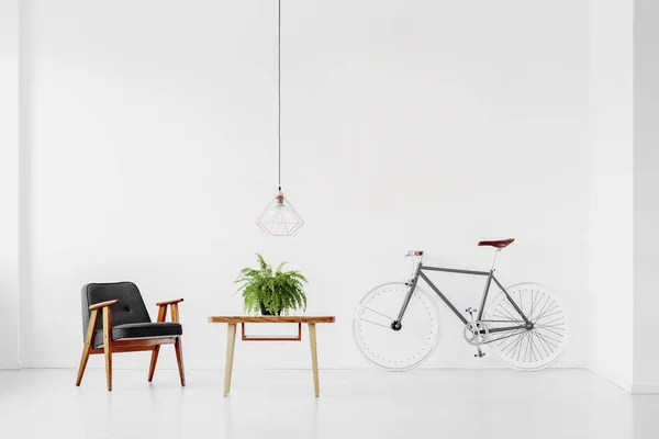 Retro fåtölj och bord med en växt i ett vitt rum interiör med en cykel. Verkligt foto — Stockfoto