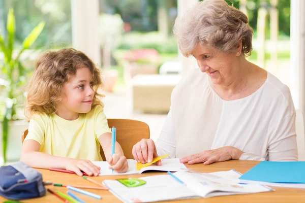 Smiling grandmother drawing with crayons with a young grandson