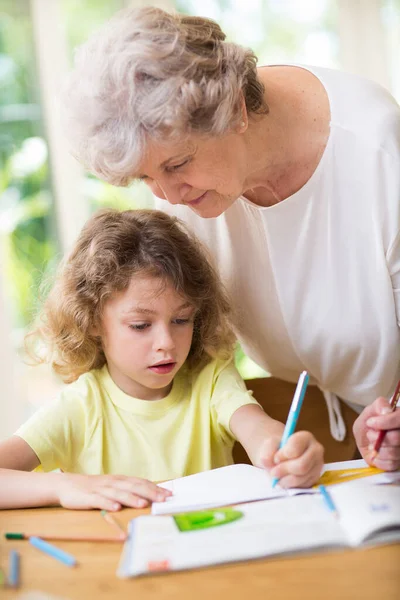 Szara babcia i jej uroczy wnuk odrabiają lekcje — Zdjęcie stockowe