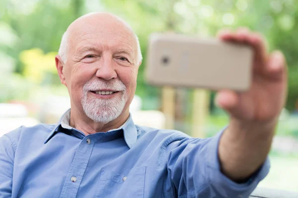 Очаровательный дедушка делает селфи с мобильного телефона. — стоковое фото