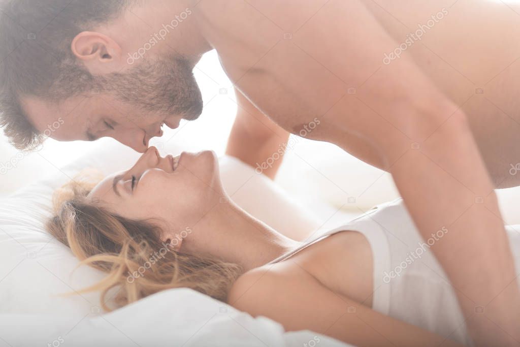 Romantic photo of sexy pair kissing and caressing in bed