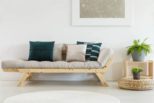 Párnák bézs kanapén ízléses nappali belső terében növényekkel fából készült állványon — Stock Fotó