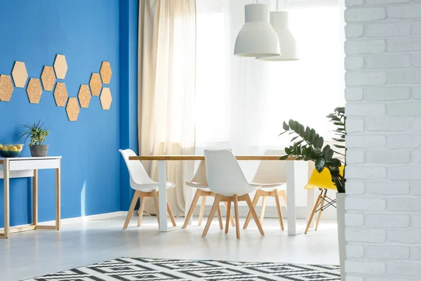 Tapis noir et blanc à motifs sur le sol de la salle à manger soignée avec table en bois et chaises blanches — Photo