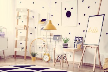 İskandinav bebek odası, küçük ahşap masa, sandalye, sevimli posterler ve sarı aksanlı