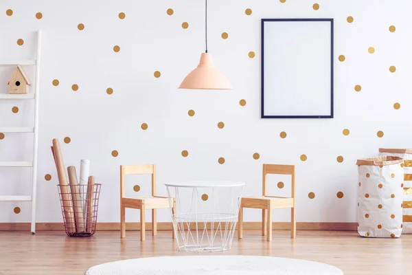 Lámpara naranja pastel sobre una pequeña mesa industrial blanca con sillas de madera en la habitación del niño —  Fotos de Stock