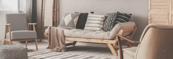 Κομψή vintage πολυθρόνα στο σύγχρονο εσωτερικό σαλόνι με φουτόν και ξύλινη Σκανδιναβική σκάλα με κουβέρτα — Φωτογραφία Αρχείου