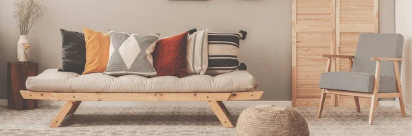 Винтажное кресло с клетчатым узором рядом с удобным бежевым диваном с подушками в красивом интерьере гостиной — стоковое фото
