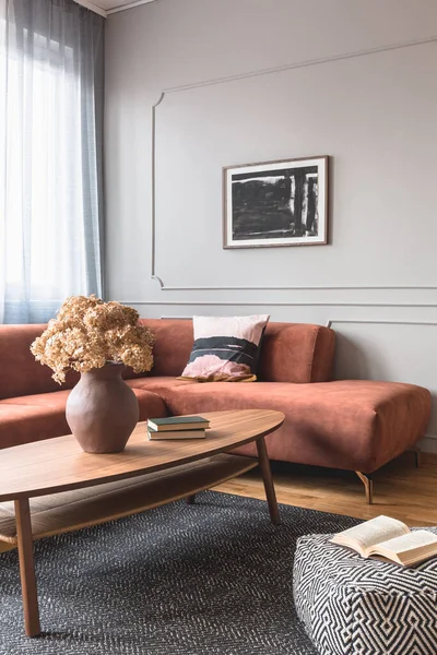Flores marrones en jarrón de cerámica en la elegante mesa de centro en el elegante interior de la sala de estar con cartel en blanco y negro en la pared gris — Foto de Stock