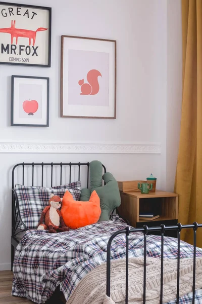 Almohadas y juguetes en una sola cama de metal en el interior del dormitorio vintage para niños —  Fotos de Stock