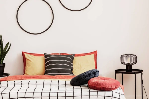 Black hoops on a white wall in an elegant bedding with orange bedding on the bed — Stok Foto