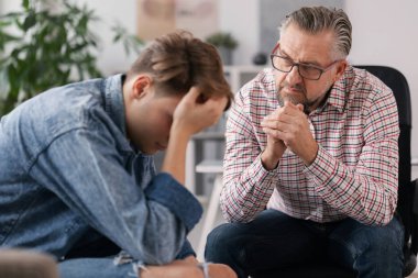 Genç çökmüş bir adam terapistiyle sorunları hakkında konuşuyor.