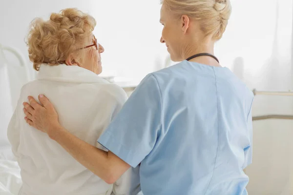 Caring Volunteer Sitting Hospice Bed Next Senior Resident Strokes Her — Stock Photo, Image