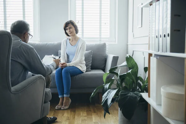一个漂亮的女人坐在灰色的沙发上与一位心理治疗师会面 — 图库照片
