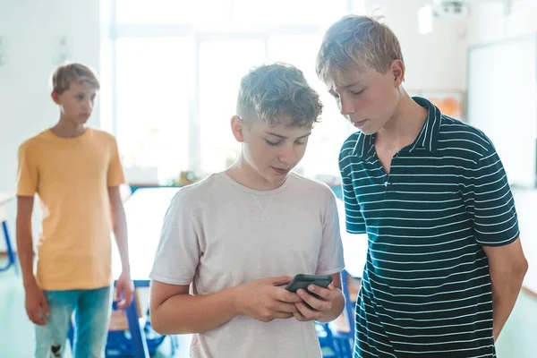 10代の男の子が学校で携帯電話で何かチェックしてる — ストック写真