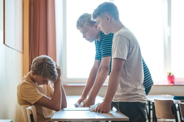 Dos Chicos Adolescentes Acosando Compañero Clase Sentado Escritorio Escuela — Foto de Stock
