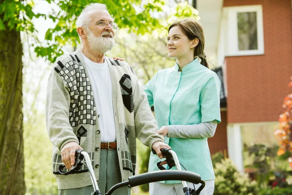 Idősebb Férfi Járkálóval Séta Közben Modern Idősek Otthonának Parkjában — Stock Fotó