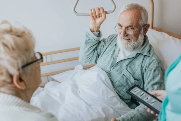 老年病人从医院的病床上站起来 用一个特殊的把手帮助自己 — 图库照片