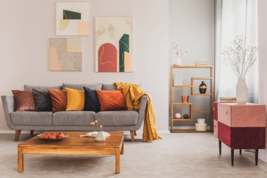 Rahat ve atmosferik oturma odası içi gri kanepe ve pastel pembe ve bordo komodinli.