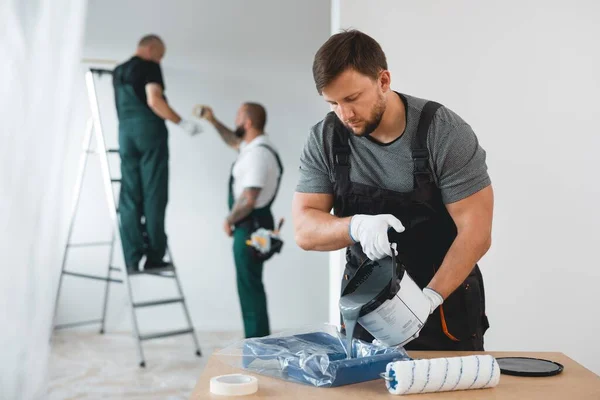 新しい建物の家の白い壁を描く効率的な改修作業員 — ストック写真