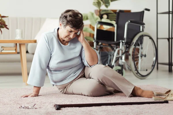 Oudere Vrouw Zit Een Vloer Naast Een Stok Heeft Hoofdpijn — Stockfoto