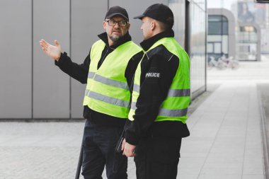 Yansıtıcı yelekli iki polis memuru şehrin sokaklarında devriye geziyor.