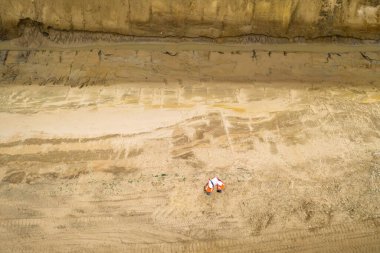 Orta sahada turuncu yelekli ve koruyucu miğferli iki yol işçisinin üst görüntüsü