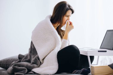 Hasta ve üşümüş genç bir kadın evinin zemininde oturuyor.