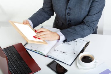 Çok çalışan iş kadını açık takvim ve dizüstü bilgisayarla masada oturuyor ve tablet üzerinde çalışıyor.