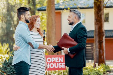 Profesyonel emlakçı, ev satın alan çifti tebrik ediyor.